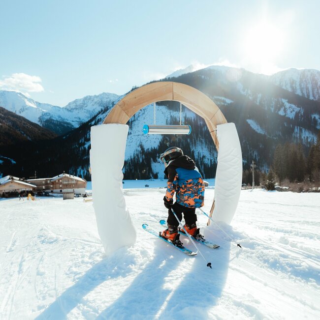 Kleiner Skifahrer führt durch Bogen im Kinderland in Obertilliach