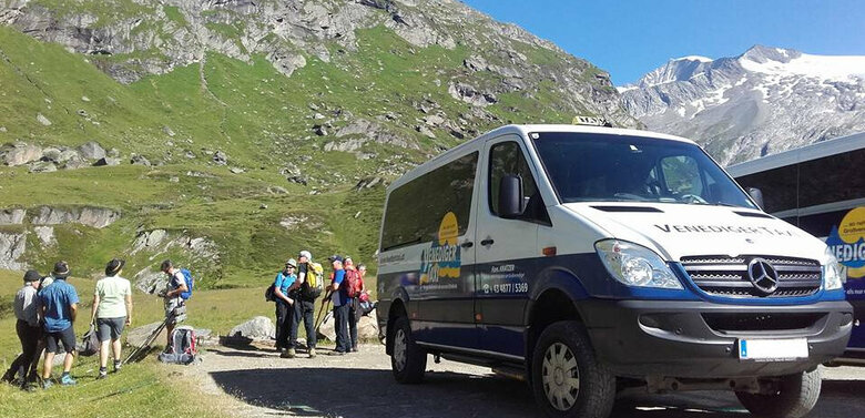 Wandertaxi Matrei in Osttirol Zwei Venediger-Wandertaxis stehen auf einem Weg vor einer imposanten Bergkulisse. Dahinter stehen mehrere Wandergäste.