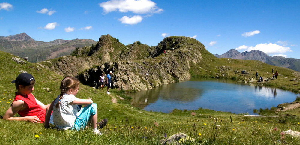 Familie beim Wandern genießt das strahlende Wetter bei einem Bergsee am Thurntaler
