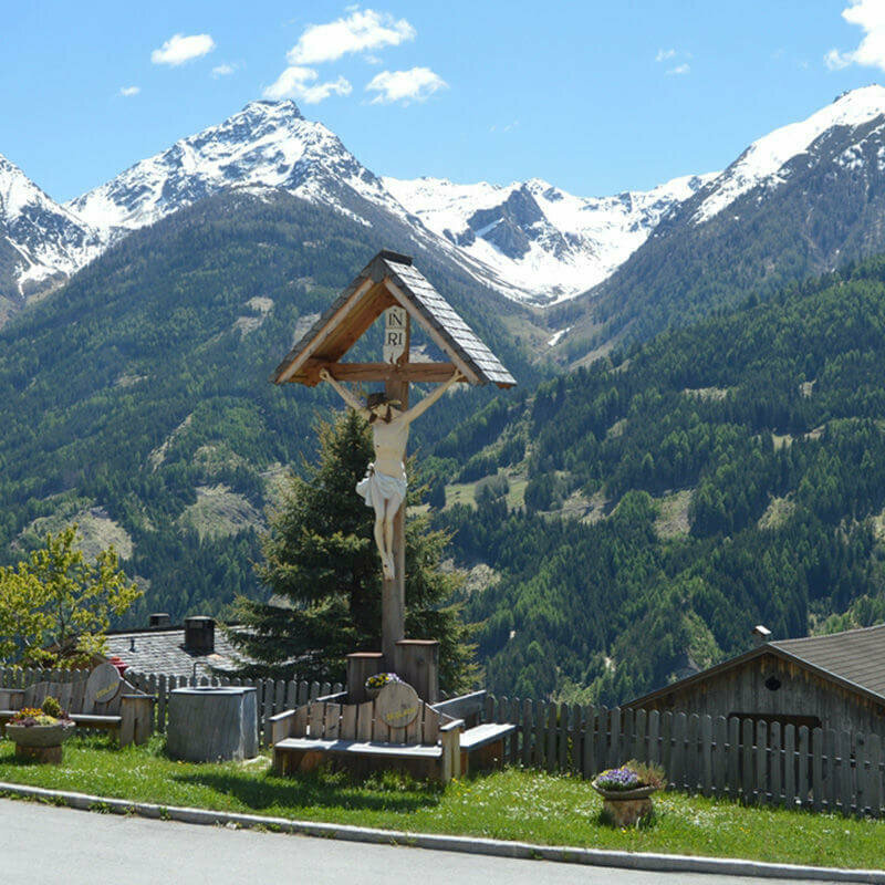 Virgentaler Sonnseitenweg Ein Bildstöckl am Straßenrand auf dem Virgentaler Sonnseitenweg. Im Hintergrund liegt noch Schnee auf den Berggipfeln.