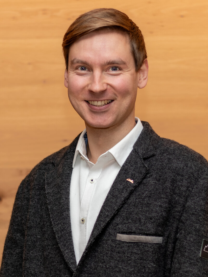 Niclas Rogl in grauer Anzugsjacke. 