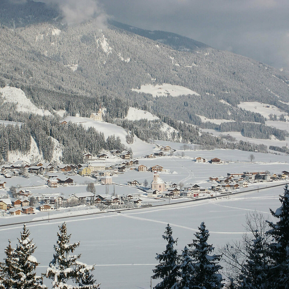 Aufnahme des Ortes Strassen von oben in winterlicher Umgebung und frisch verschneite Wäldern.
