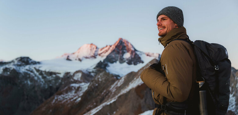 Wanderer nach Sonnenuntergang am Figerhorn mit dem schneebedeckten Großglockner im Hintergrund.