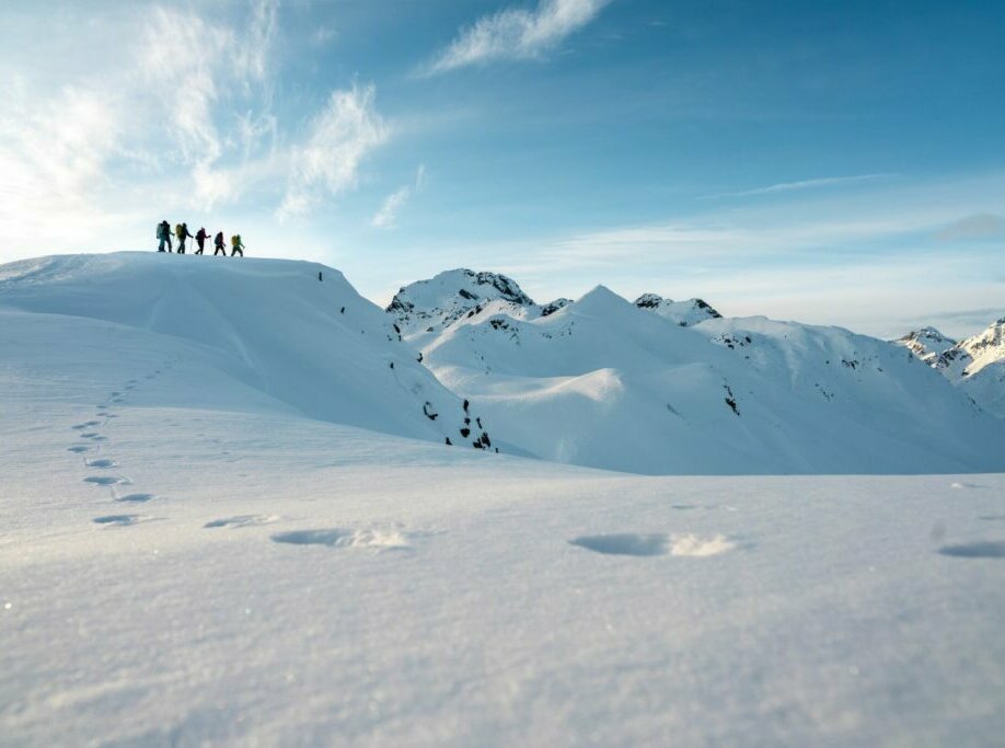 Eine Gruppe auf Rangerwanderung im Schnee. Im Vordergrund sind einige Spuren im tiefen Schnee.