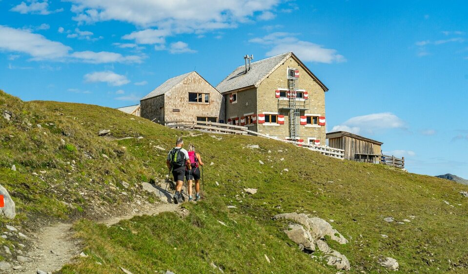 Zwei Wanderer erreichen die Salmhütte auf Etappe 4 der Glocknerkrone in Kals am Großglockner, Osttirol.