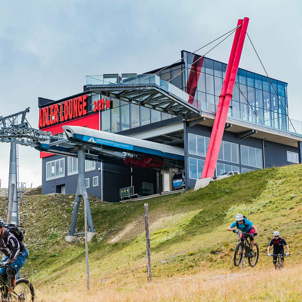 GG Resort Kals Matrei Adler Lounge Zwei talwärts fahrende Mountainbiker unterhalb der Bergstation der Gondelbahn im Großglockner Resort Kals-Matrei