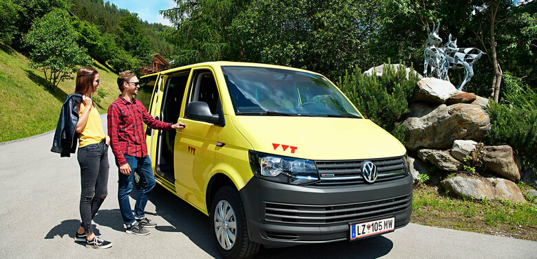 Auf dem Bus sind zwei Wanderer zu sehen, die gerade in das gelbe Wanderbus einsteigen