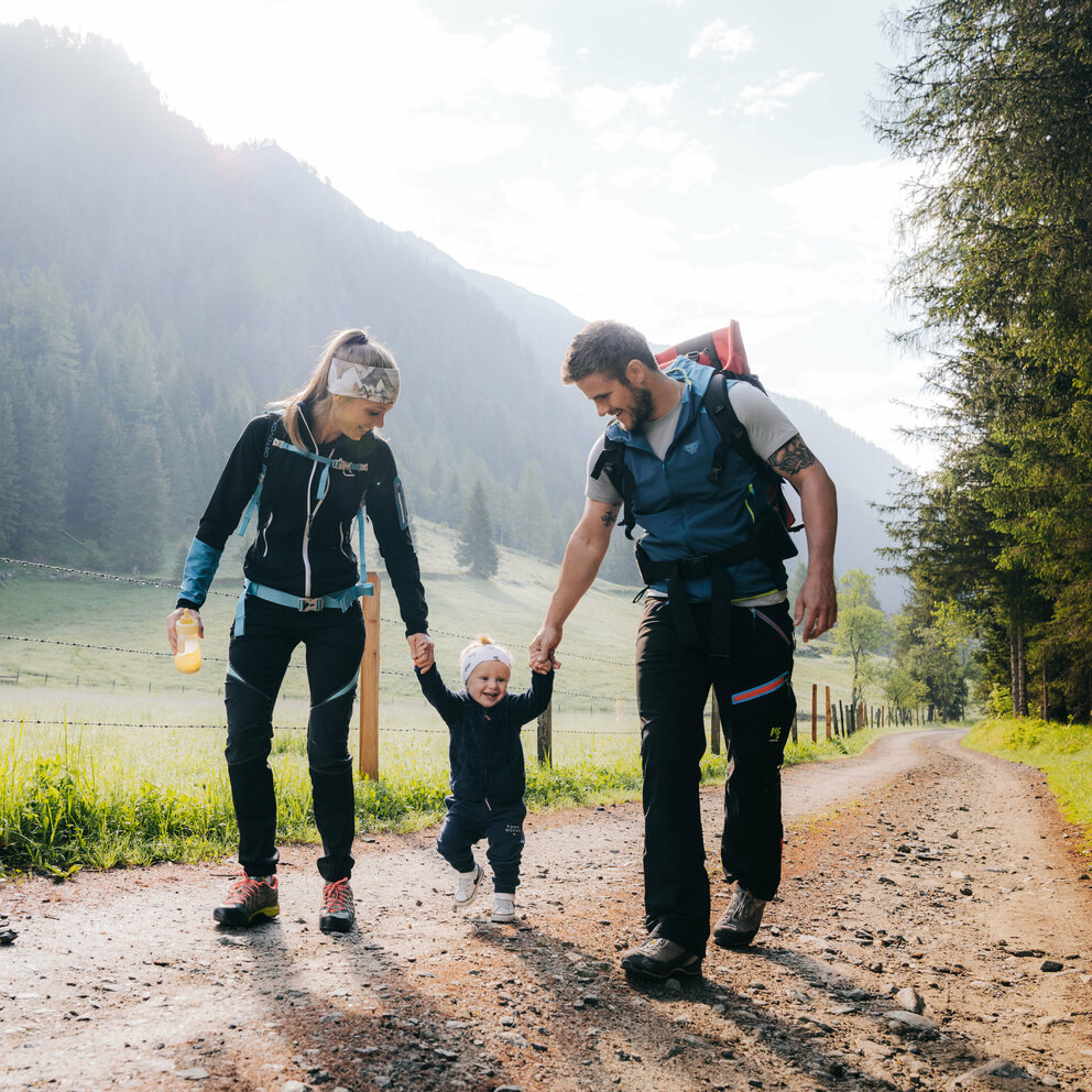 Eine Mann und eine Frau mit ihrem kleinen Kind dazwischen wandert im Kristeinertal.