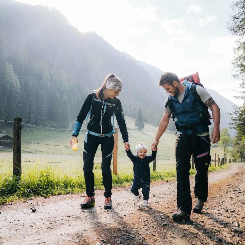 Eine Mann und eine Frau mit ihrem kleinen Kind dazwischen wandert im Kristeinertal.
