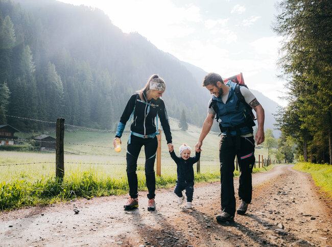Eine Mann und eine Frau mit ihrem kleinen Kind dazwischen wandert im Kristeinertal.