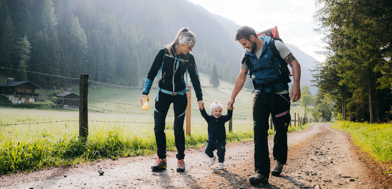 Eine Mann und eine Frau mit ihrem kleinen Kind dazwischen wandert im Kristeinertal.