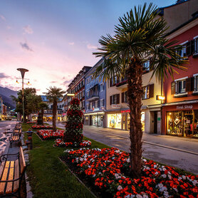 Die Blumenbeete und Bänke am Lienzer Hauptplatz in der Abenddämmerung. Der Himmel färbt sich leicht rosa.