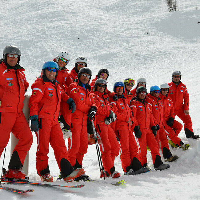 Team der Skischule White Element im Skizentrum Hochpustertal mit ihren auffälligen roten Skianzügen auf der Piste.