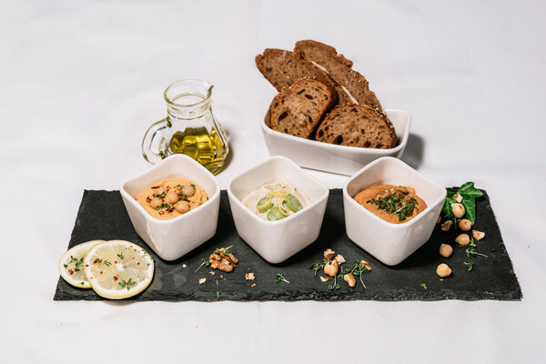 Aufstrichvariation Schieferplatte mit Aufstrichvariation, dunkles Brot und Öl.