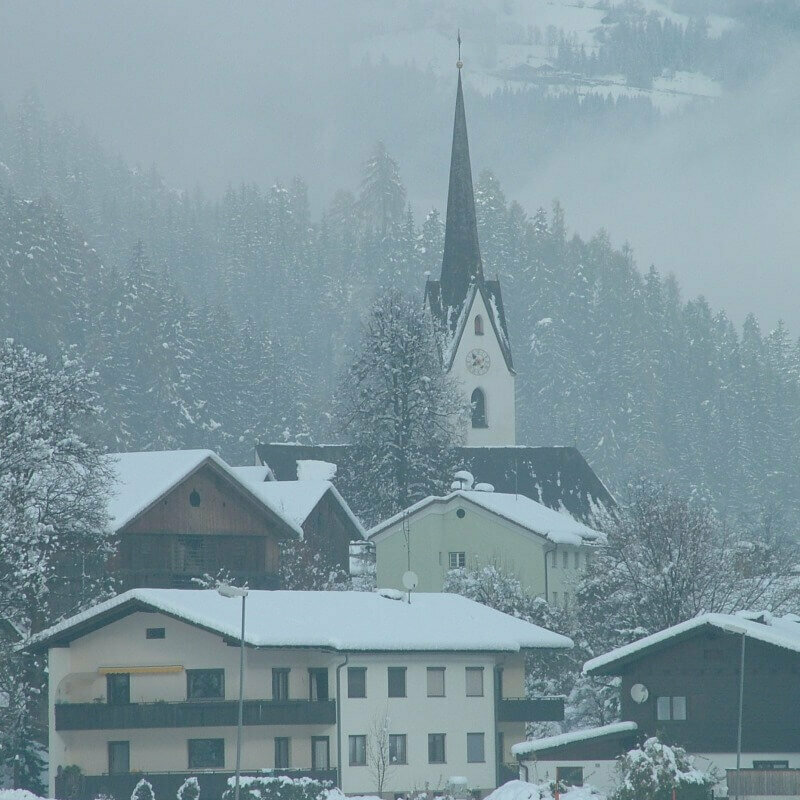 Leisach in Osttirol mit Dächern voller Schnee und der Kirche im Hintergrund.