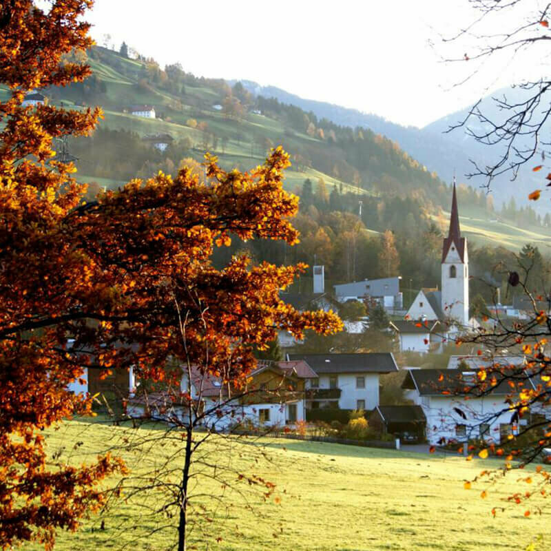 Ortsbild von Gaimberg aus der Entfernung im Herbst bei klarer Herbstluft und sich verfärbenden Bäumen.
