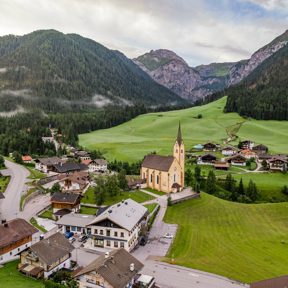 Das Ortszentrum des idyllischen Bergdorfes Kartitsch mit seiner Pfarrkirche und einigen Wohnhäusern im Sommer aus der Vogelperspektive