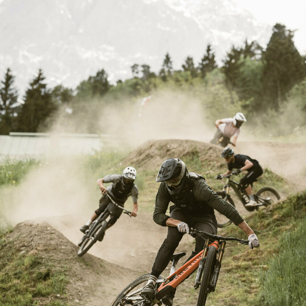 Bikepark Abfahrt Gruppe junger Männer fährt auf einem Trail im Lienzer Hochstein Bikepark ab.
