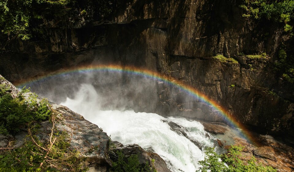 Über einem tosenden Wasserfall ist ein Regenbogen entstanden.