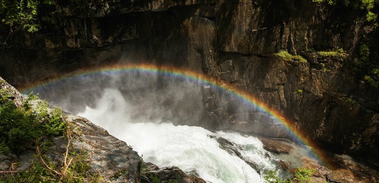 Über einem tosenden Wasserfall ist ein Regenbogen entstanden.