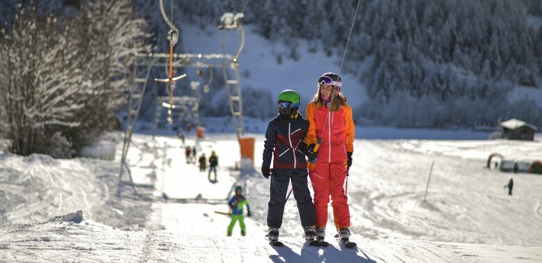 Kinder werden der Reihe nach vom Schlepplift an den Startpunkt der Pistenabfahrt gebracht.