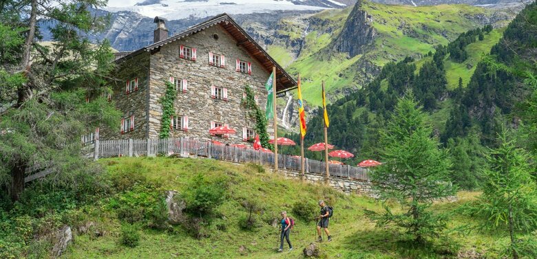 Weitwandern auf der Glocknerkrone in Osttirol, Etappe 3: Blick auf das Kalser Tauernhaus, umgeben von Bergen und Natur im Kalser Dorfertal.