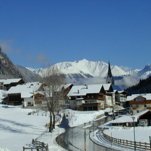 Hopfgarten Ein Blick auf das verschneite Hopfgarten i. D., im Hintergrund sind die Kirche und die Berge zu sehen.