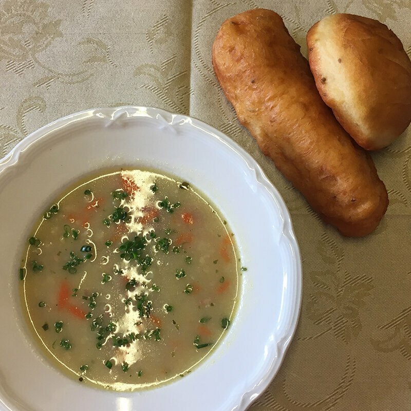 Ein Teller Suppe mit zwei Stück Niggelan daneben.