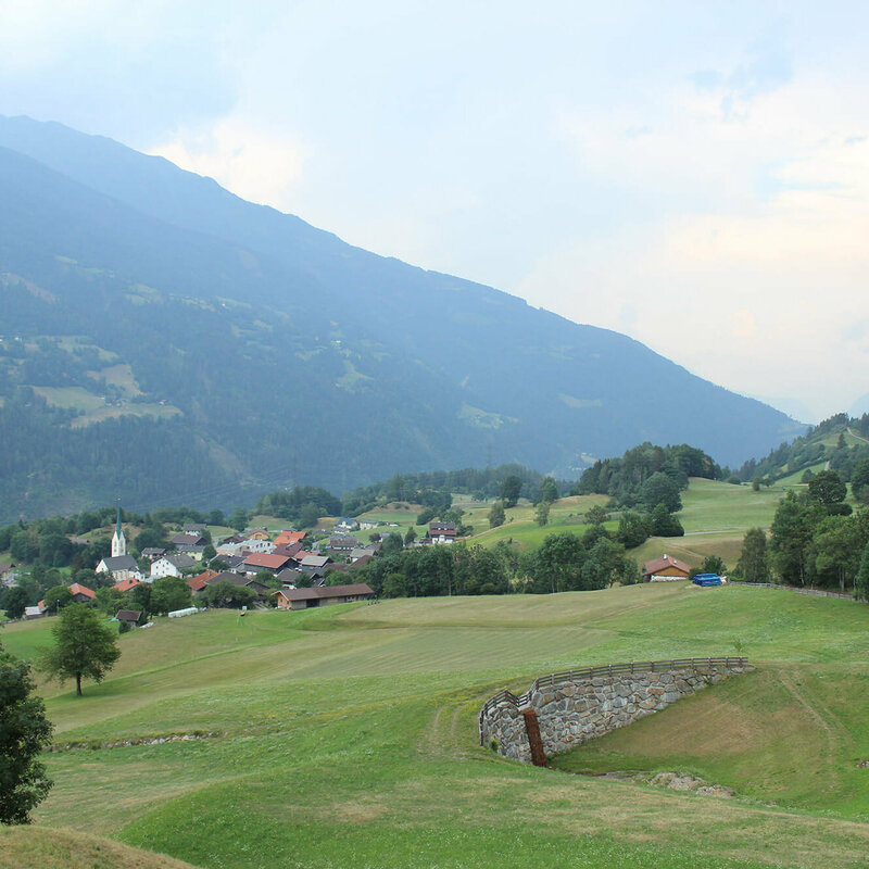 Blick auf eine große Wiese mit der Gemeinde Schlaiten im Hintergrund.