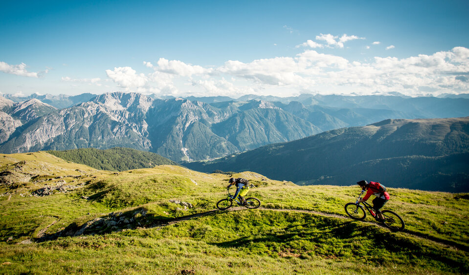 Radfahren mit einzigartigem Panorama Zwei Radfahrer auf einem schmalen Trail mit einzigartigem Bergpanorama.