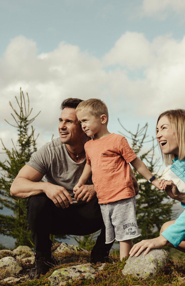 Eine junge Familie schaut gespannt in die Ferne auf der Kindermeile Obertilliach