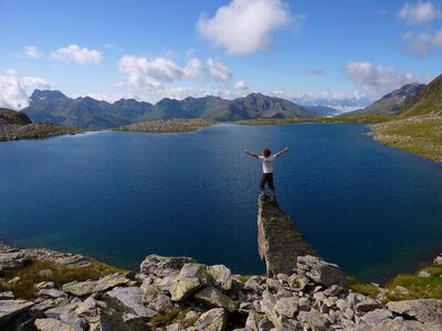 Oberseitsee unter der Seespitze Blick auf den tiefblauen Oberseitsee unter der Seespitze in St. Jakob i. D.. Ein Mann steht auf einem Stein, der scheinbar über das Ufer hinausragt. Er streckt sich dem sommerlich-blauen Himmel entgegen.