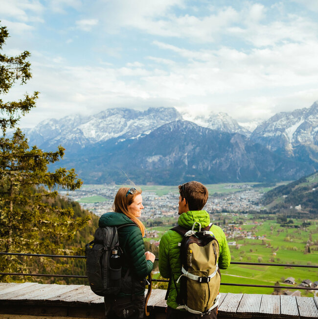 Zwei Wanderer genießen den Ausblick vom Helenenkirchl auf die Stadt Lienz und die noch zum Teil schneebedeckten Gipfel der Lienzer Dolomiten.