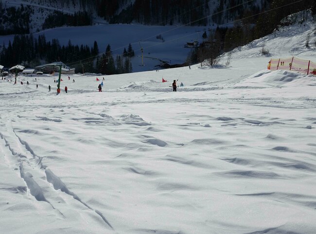 Prägraten Bichllift Schlepper Blick auf ein Schneefeld vor dem Bichllift Schlepper. Im Lift fahren mehrere Personen. Dahinter ist eine Slalomstrecke aufgebaut.