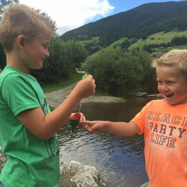 Zwei Jungs stehen sich gegenüber und spielen mit einem Papierspielzeug.