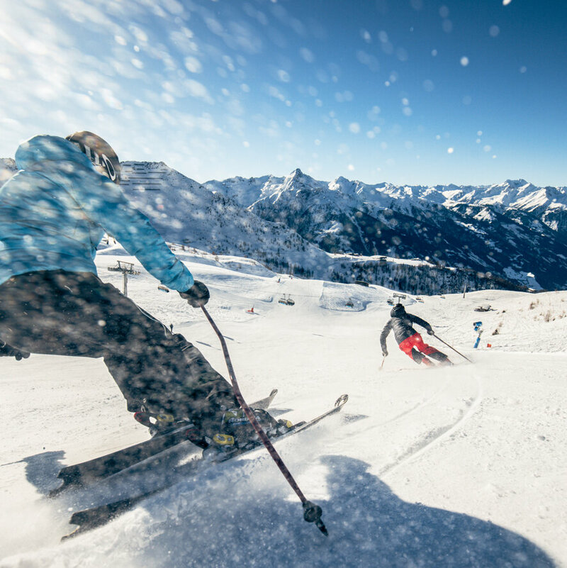Zwei Skifahrer:innen bei der sonnigen Abfahrt im Großglockner Resort