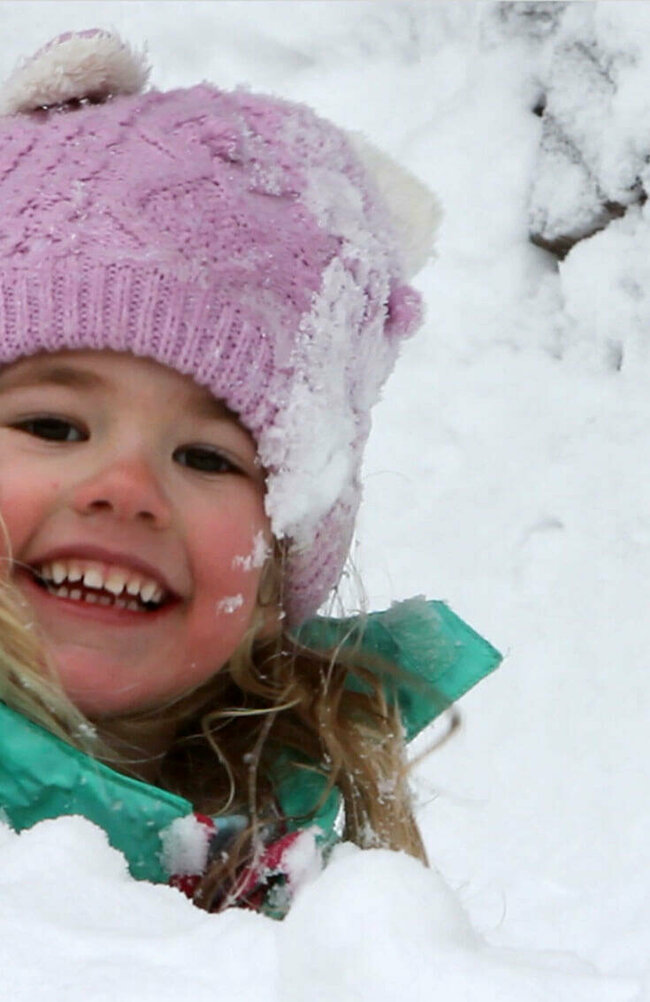 Ein Kind spielt fröhlich im frischen Schnee
