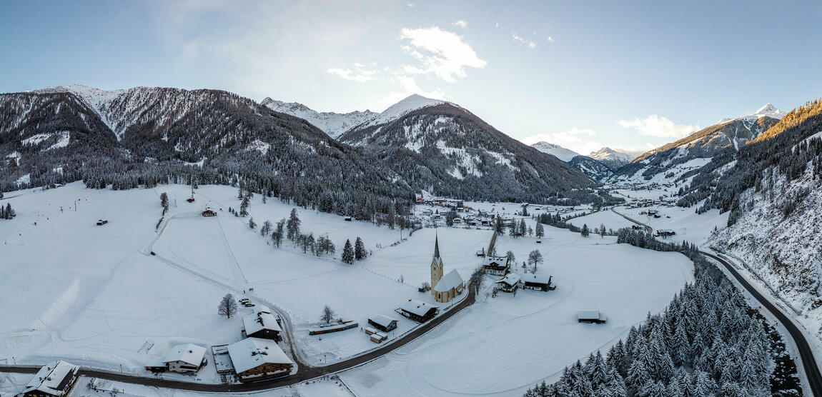 Der Blick aus der Vogelperspektive auf das verschneite Defereggental mit imposanten Bergen im Hintergrund.