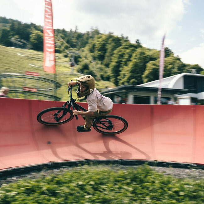 Bikepark Lienz - Pumptrack Junge fährt auf einem Mountainbike mit hohem Tempo durch eine Steilkurve im Bikepark-Lienz Pumptrack am Hochstein.