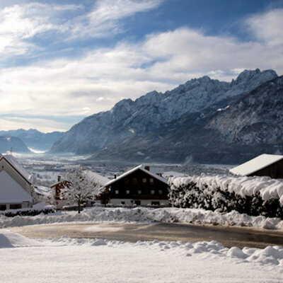 Thurn mit der Kirche im Winter und den dahinterliegenden Bergen.
