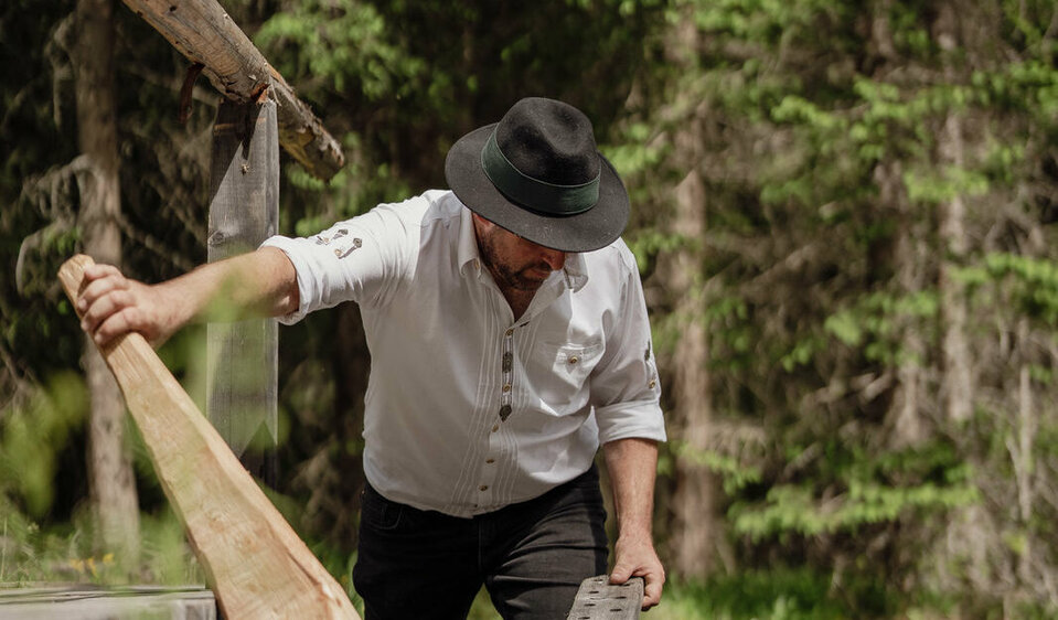 Ein Mann mit einem Lodenstampf, einem traditionellen Werkzeug zum Bearbeiten von Lodenstoff.