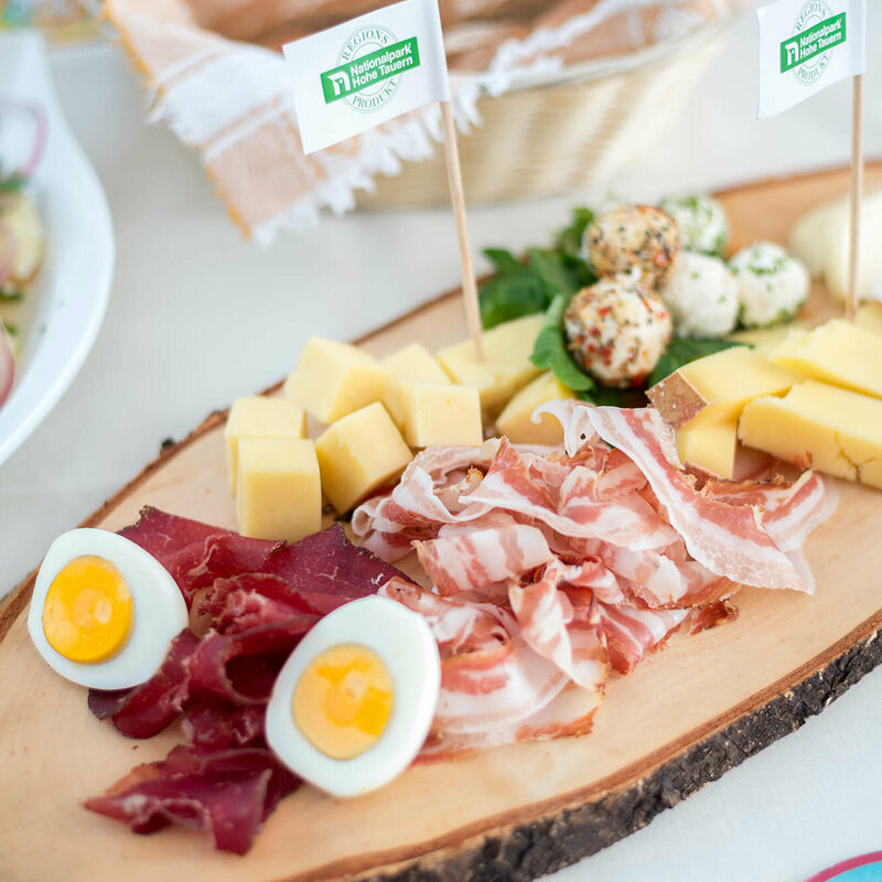 Brettljause mit verschiedenen Käsesorten in Würfel geschnitten, feinen Speck- und Henkelescheiben und hartgekochten Eiern.