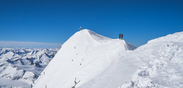 Zwei Skitourengeher:innen erklimmen den Gipfelgrat des Großvenediger