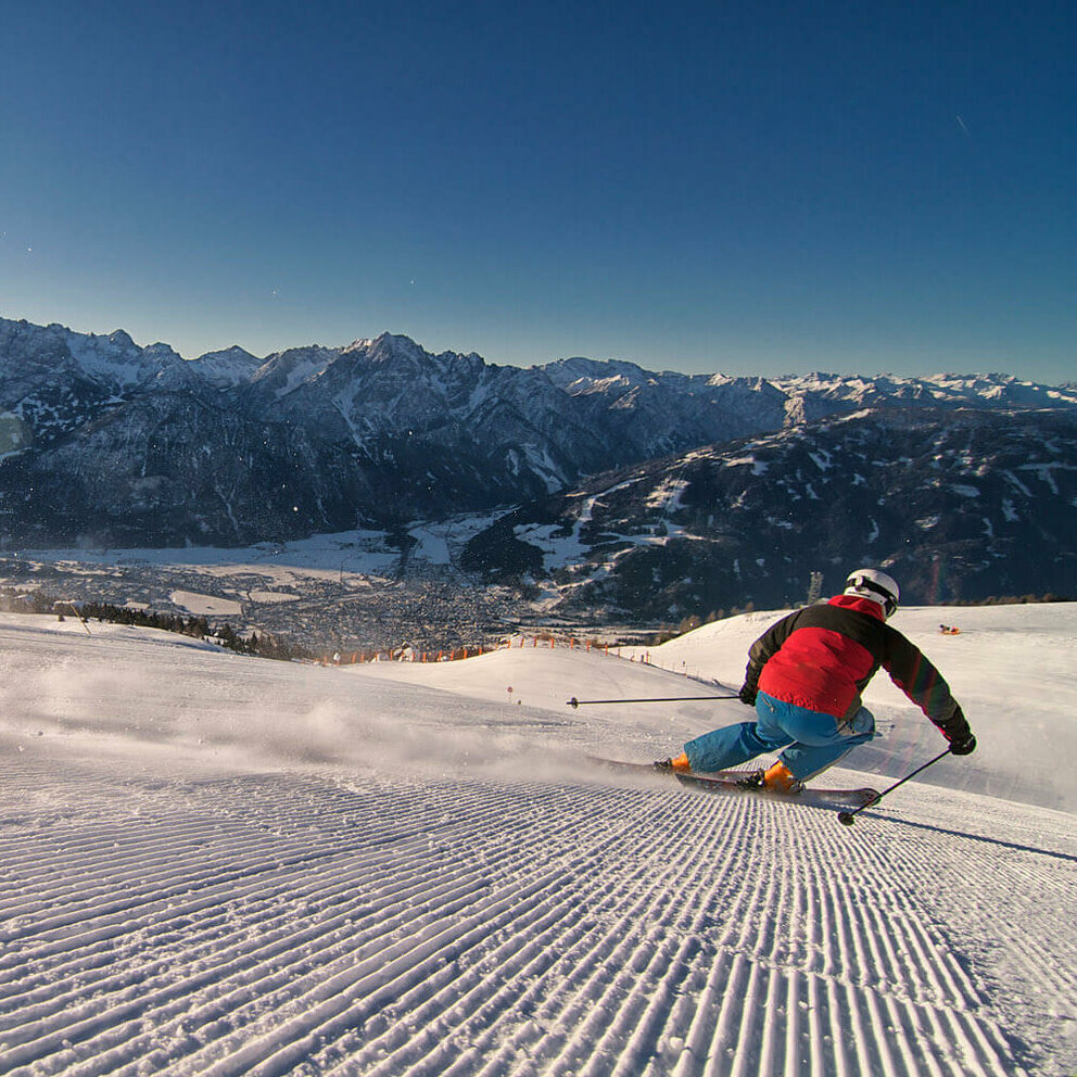 Ein Skifahrer mit rot-schwarzer Jacke und blauer Hose zieht seine Spuren im frisch präparierten Skigebiet Zettersfeld in Lienz.