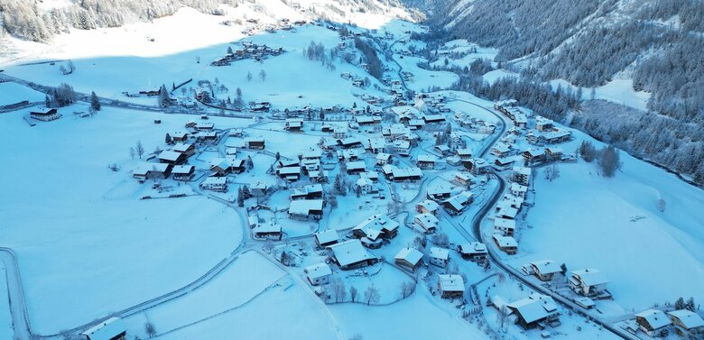 Prägraten am Großvenediger mit schneebedeckten Dächern im Winter aus der Luft fotografiert.