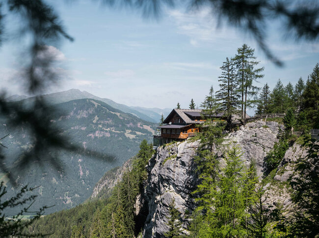 Blick auf die Dolomitenhuette an einem schönen Tag, durch einige Zweige fotografiert.