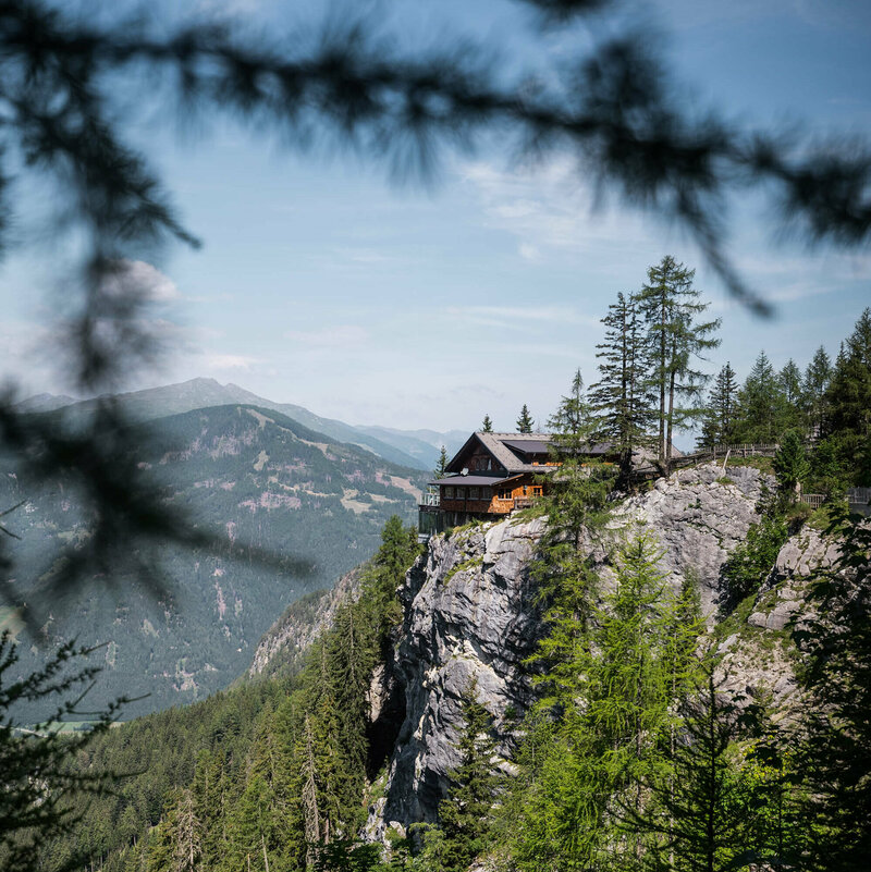 Blick auf die Dolomitenhuette an einem schönen Tag, durch einige Zweige fotografiert.