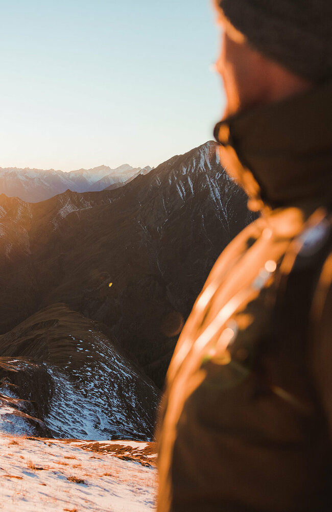 Figerhorn Wanderer betrachtet am Figerhorn, wie die Sonne langsam hinter den umliegenden Bergen untergeht.