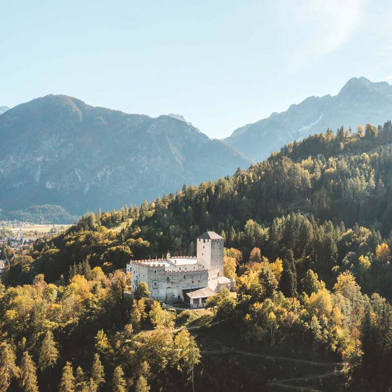 Schloss Bruck thront auf der kleinen Erhebung im goldenen Herbst bei strahlendem Sonnenschein.