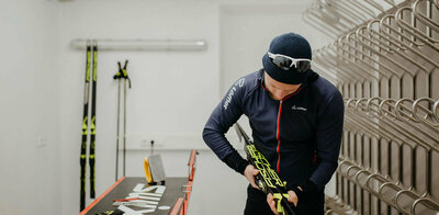 Ein Person ist im Wachsraum des Biathlonzentrum Obertilliach gerade dabei, die Langlaufski zu wachsen